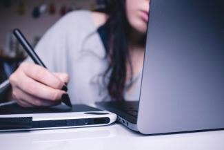 woman using drawing pad while sitting in front of laptop by Josefa  nDiaz courtesy of Unsplash.